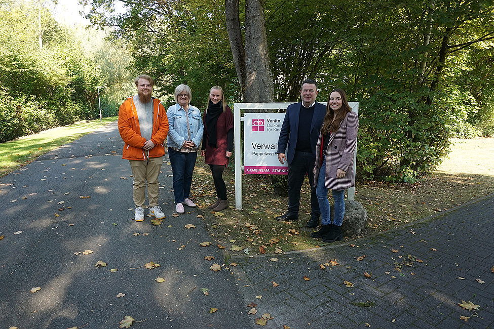Fünf Personen stehen neben Venito-Verwaltungsschild im Park
